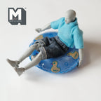 1:12 scale miniature round pool float in blue with a yellow cartoon duck print, shown with a poseable figure sitting in it