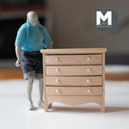 1:12 scale miniature 4 drawer chest in bare wood with round knobs and a curved apron, shown beside an artist figure