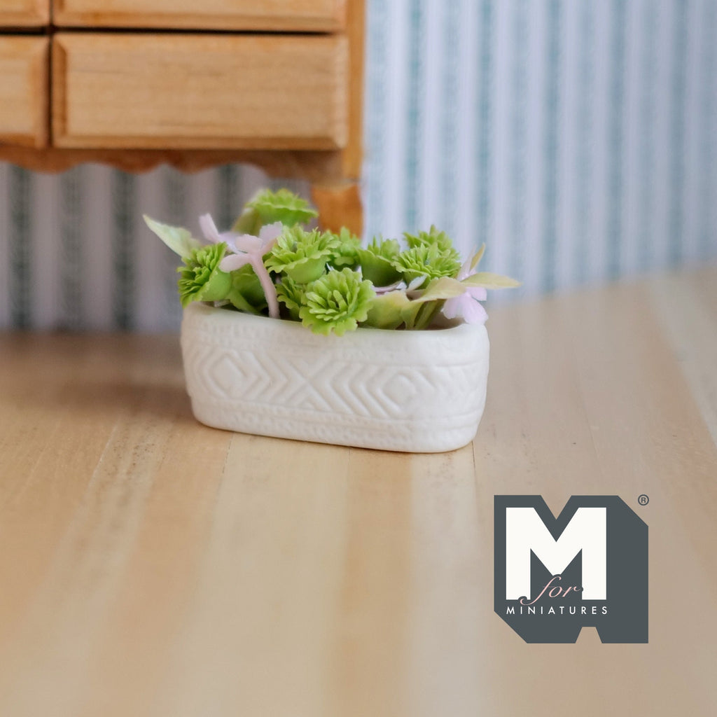 1:12 scale miniature flowers in a long white planter trough with green leaves, shown on a wood floor