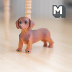 1:12 scale miniature cast resin standing dachshund puppy in brown, shown on a light wood floor