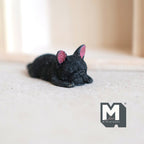 1:12 scale miniature cast resin sleeping French bulldog puppy in black with pink ears, shown lying on a light floor