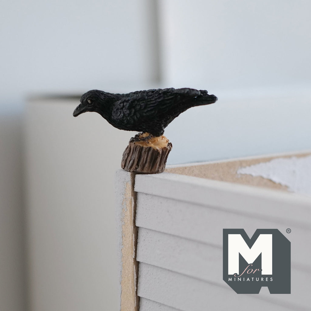 1:12 scale miniature cast resin crow on tree stump, black bird perched on a brown stump, shown on a table edge