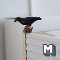 1:12 scale miniature cast resin crow on tree stump, black bird perched on a brown stump, shown on a table edge