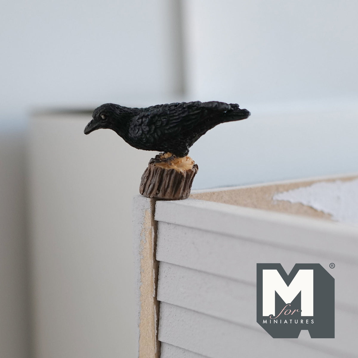 1:12 scale miniature cast resin crow on tree stump, black bird perched on a brown stump, shown on a table edge