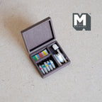 1:12 scale miniature paint set in wooden box with paint tubes and brushes, lid open, shown on a linen surface