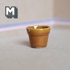 1:12 scale miniature glazed ceramic tree pot in amber brown, large size, tapered shape, shown on a gray floor