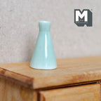 1:12 scale miniature mint green ceramic cone shaped bottle vase with narrow neck, shown on a wood dresser