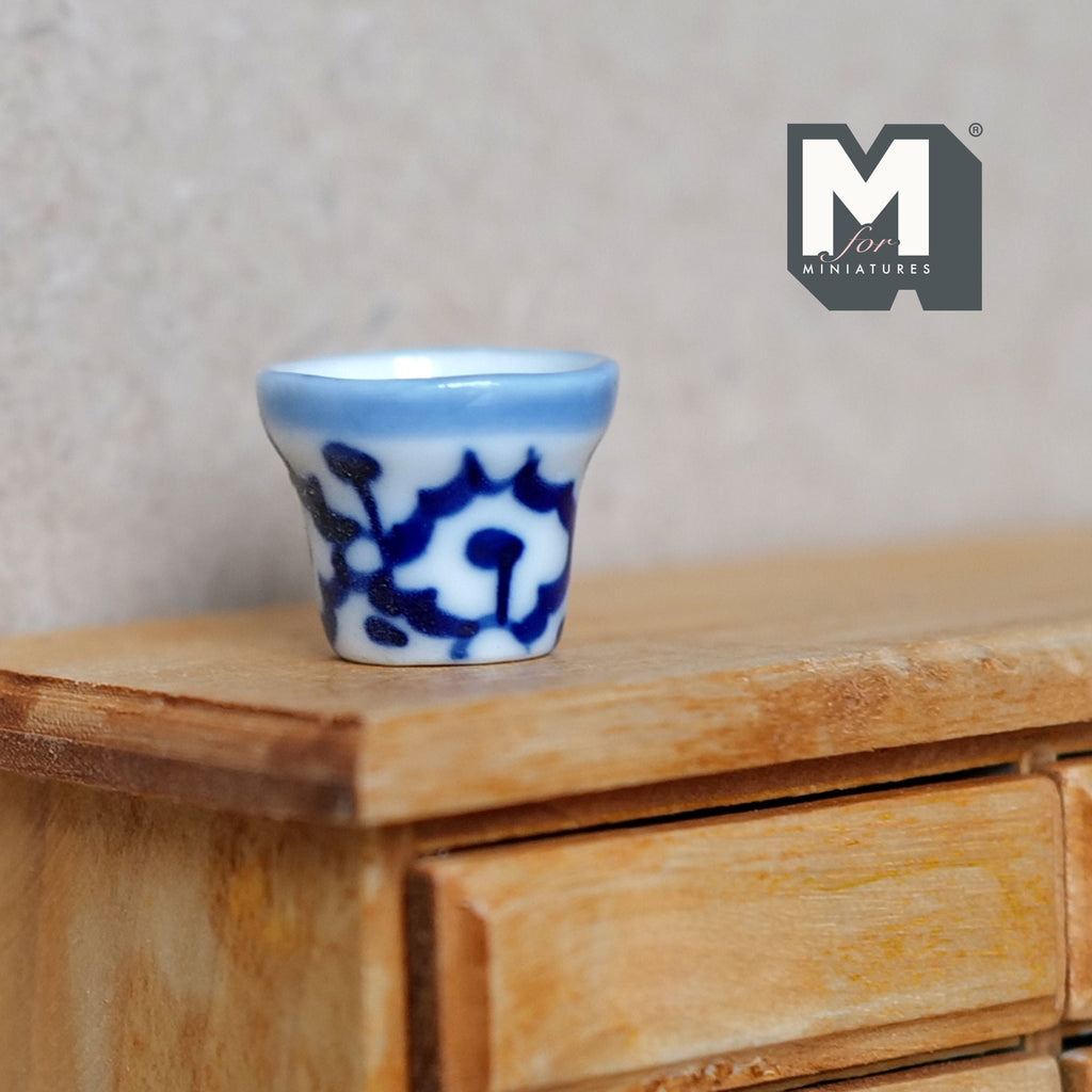1:12 scale miniature ceramic round flower pot with blue and white pattern, shown on a wood dresser