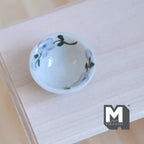 1:12 scale miniature light blue ceramic bowl with painted leaf pattern, shown on an unpainted wood table