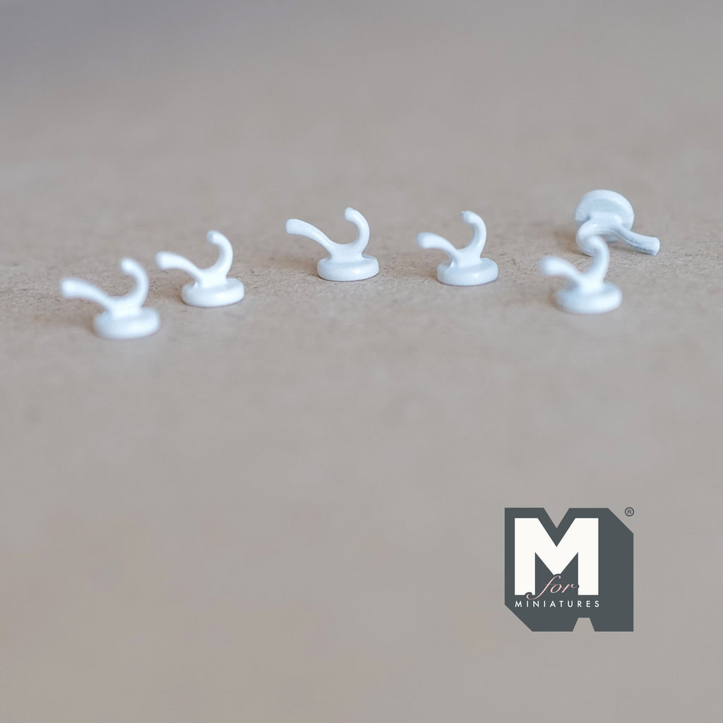 1:12 scale miniature wall hooks in white, set of 6, single curved hooks with round bases, shown on a tan surface