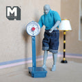 1:12 scale miniature blue standing weighing scale with round dial, non working, shown with a poseable figure