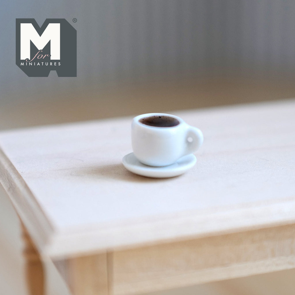 1:12 scale miniature cup of black coffee and saucer, white cup shown on a light wood table