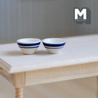 1:12 scale miniature ceramic bowls with blue stripe rim, set of 2 in white and blue, shown on a bare wood table