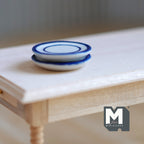 1:12 scale miniature ceramic plates in white with blue colored rim, set of 2, shown stacked on a wood table