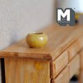 1:12 scale miniature ceramic round planter pot in yellow green glaze, shown empty on a wood dresser