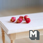 1:12 scale miniature pomegranates in red with crown tops, set of 5, shown loose on a bare wood table