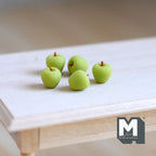 1:12 scale miniature apples in green with brown stems, set of 5, shown loose on a bare wood table