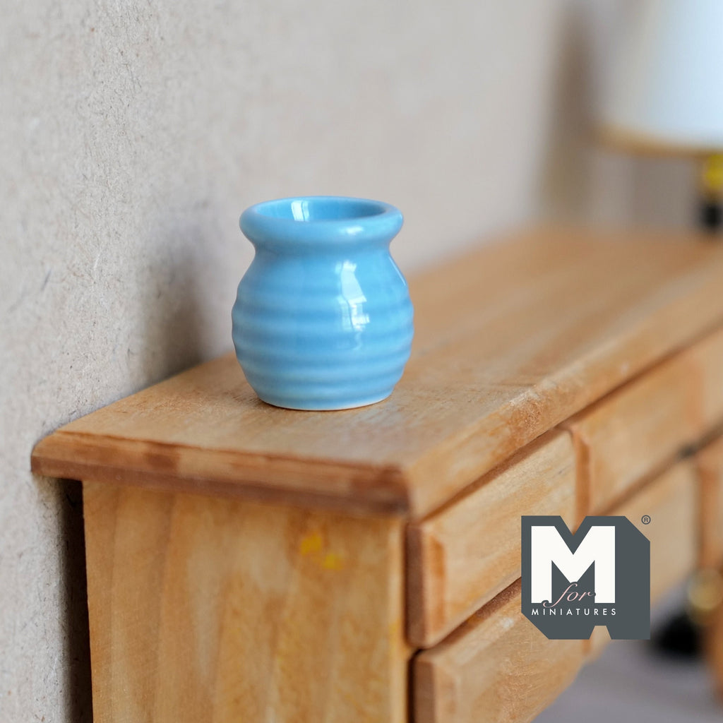 1:12 scale miniature light blue ceramic flower pot with ribbed sides, shown on a wood dresser