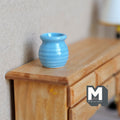 1:12 scale miniature light blue ceramic flower pot with ribbed sides, shown on a wood dresser