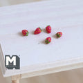 1:12 scale miniature red strawberries with green tops, set of 5, scattered on a light wood table