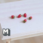 1:12 scale miniature red strawberries with green tops, set of 5, scattered on a light wood table