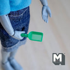1:12 scale miniature green cat litter scoop with slotted head, shown held by a figure for scale