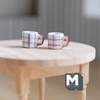 1:12 scale miniature ceramic coffee mugs in blue plaid on white with red handles, set of 2, shown on a round wood table