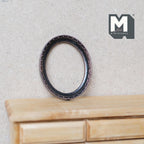 1:12 scale miniature ornate oval picture frame in bronze with beaded edge, empty frame leaning on a wood dresser