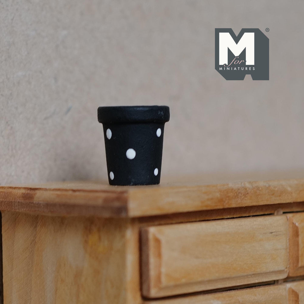 1:12 scale miniature ceramic tapered polka dot flower pot in black with white dots, shown on a wood dresser