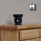 1:12 scale miniature ceramic tapered polka dot flower pot in black with white dots, shown on a wood dresser
