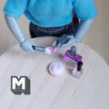 1:12 scale miniature makeup set in purple, set of 5 with perfume bottle, lipsticks and brush, on a round table with a figure