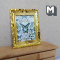 1:12 scale miniature butterfly canvas print in an ornate gold frame, shown leaning on a wood dresser