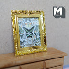 1:12 scale miniature butterfly canvas print in an ornate gold frame, shown leaning on a wood dresser