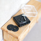 1:12 scale miniature metal turntable in black with clear dust cover and 2 vinyl records, non working, on a dresser