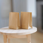 1:12 scale miniature kraft paper shopping bags in plain brown, set of 2, standing on a round wood table