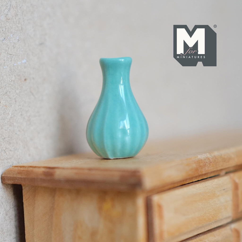 1:12 scale miniature green ceramic bud vase with flared neck and ribbed body in aqua green, shown on a wood dresser
