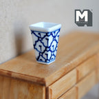 1:12 scale miniature ceramic square vase with blue pattern on white and a flared rim, shown on a wood dresser