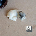 1:12 scale miniature sleeping pug dog figurine in beige cast resin with dark face, curled up on a tan surface