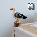 1:12 scale miniature cast resin seagull on post, white with gray and black wings and orange beak, perched on a table edge