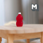 1:12 scale miniature red ketchup bottle with white cap and contoured sides, shown on a round wood table
