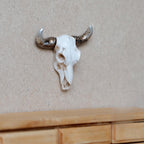 1:12 scale miniature cast resin bull skull wall decor in white with long brown horns, shown mounted on a beige wall