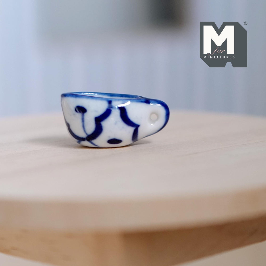 1:12 scale miniature ceramic cream boat with handle, white with hand painted blue pattern, shown on a round wood table