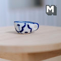 1:12 scale miniature ceramic cream boat with handle, white with hand painted blue pattern, shown on a round wood table