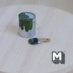 1:12 scale miniature paint can with brush, set of 2, silver can with dark green paint, shown on a round wood table