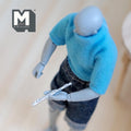 1:12 scale miniature metal flute in silver, musical instrument, shown held by a figure in a blue sweater
