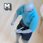 1:12 scale miniature metal flute in silver, musical instrument, shown held by a figure in a blue sweater
