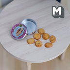 1:12 scale miniature butter cookie tin with 7 cookies, round pink floral lid, shown open on a round wood table