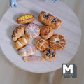 1:12 scale miniature assorted resin bakery buns, set of 11, glazed and braided breads shown on a round wood board