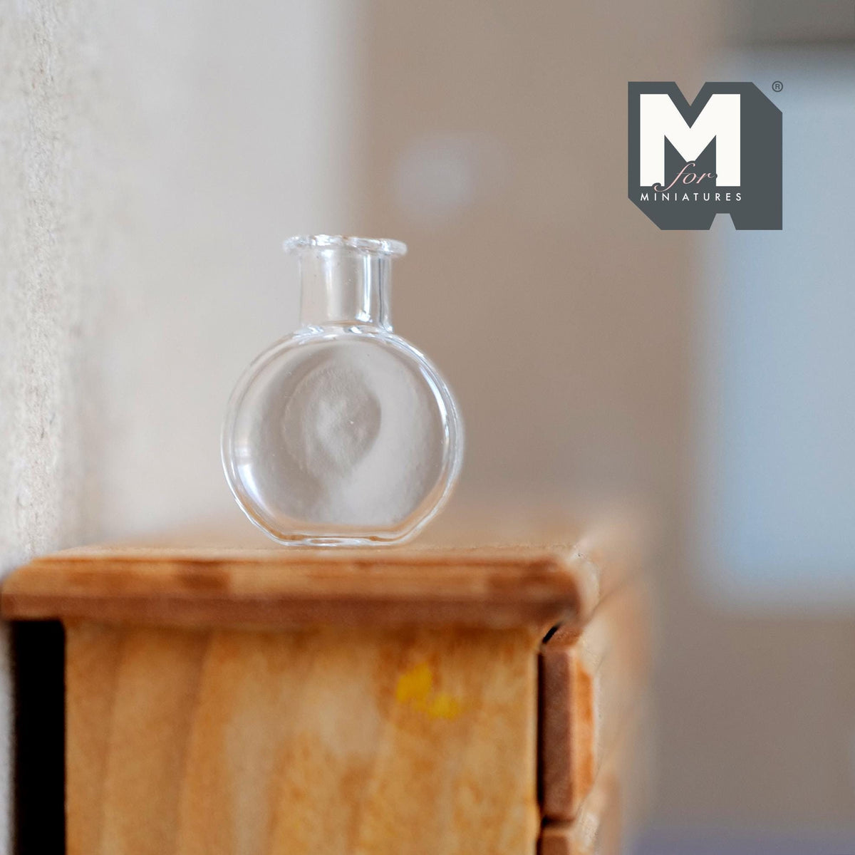 1:12 scale miniature clear glass flower vase with round body and flared rim, shown on a wood dresser