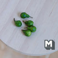 1:12 scale miniature green pears with dark stems, set of 5, shown on a round whitewashed wood table